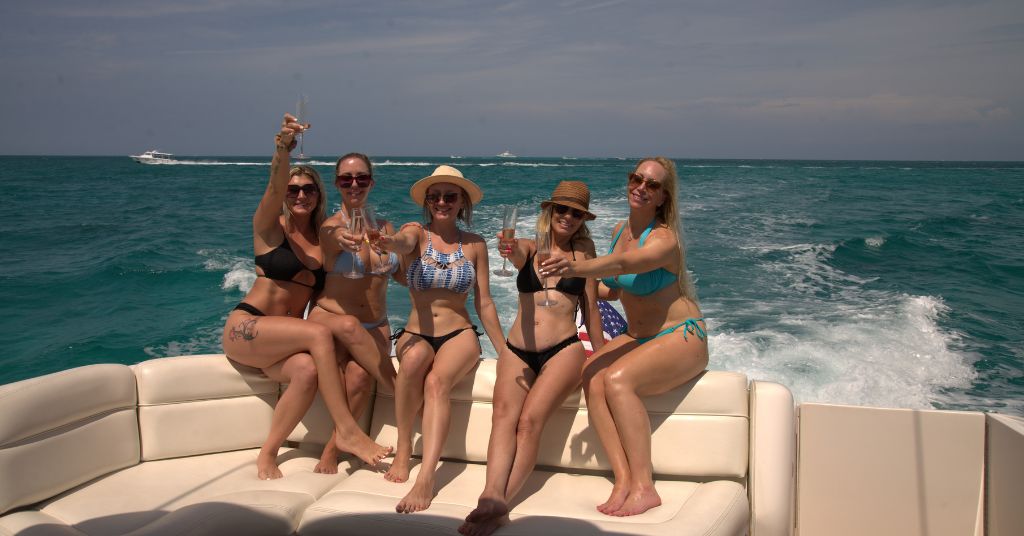 Friends relaxing and sunbathing on the open front deck layout of a private motor vessel during a spring cruise